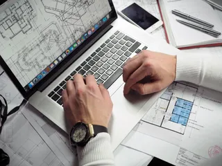 Anlagenplanung mit Bauplänen und Laptop
