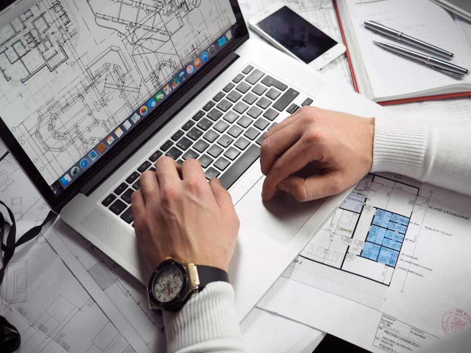 Anlagenplanung mit Bauplänen und Laptop